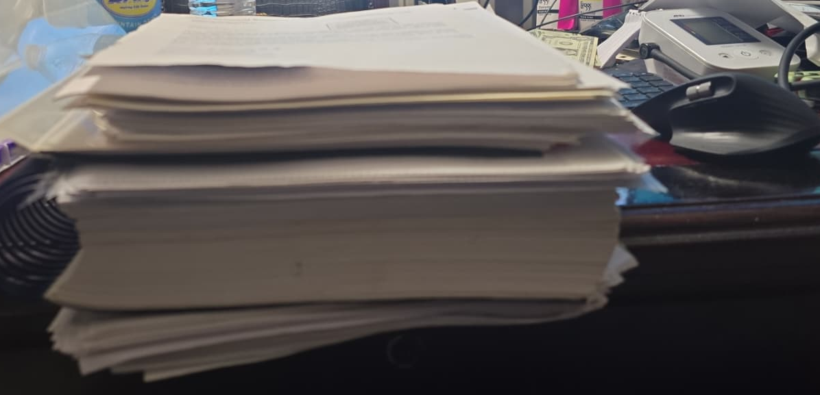 A side view of a tall stack of folders and court papers on a desk — part of the files Leroy kept from every battle over the years.